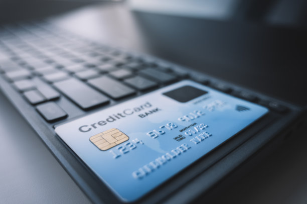 通过互联网用信用卡付款。黑色的笔记本电脑键盘上放着一张蓝色的塑料银行卡。NFC卡支付读取图片下载