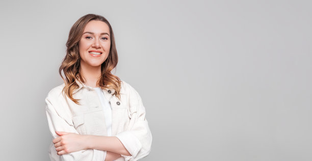 一个年轻的微笑的学生女孩的肖像，波浪的头发孤立在白色的背景图片下载