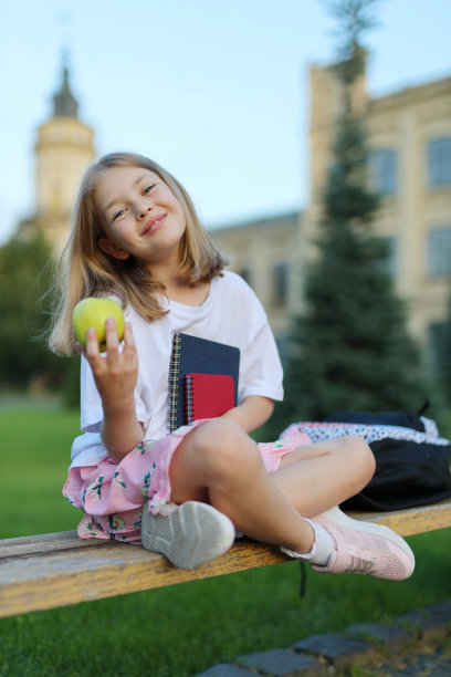 可爱的小女生手里拿着苹果和笔记本，午休。图片下载