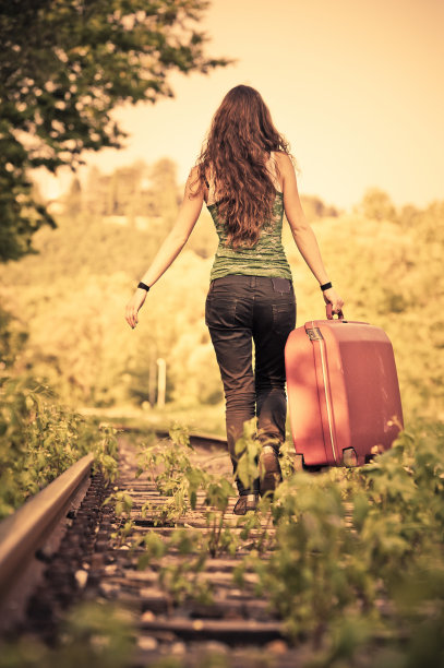 孤独的女孩在铁路上带着她的包走了图片下载