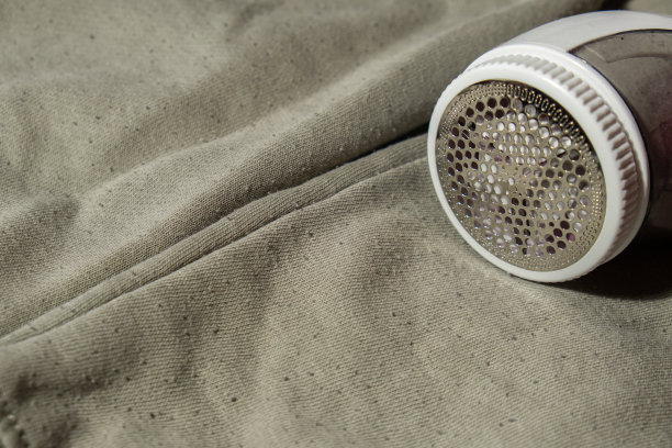 摇粒剃须刀。一种磨粒衣物的装置。防长毛绒织物剃须刀。电动便携式羊毛衫毛球除绒机，用于去除腈纶或羊毛羊毛衫上的毛球。可持续时尚生活方式，减少服装浪费图片下载