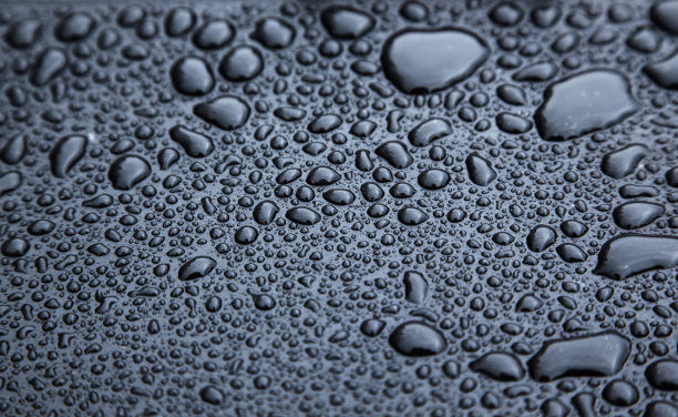 黑色橡胶表面上的雨滴特写图片下载