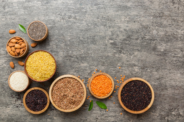 各种超级食物在彩色背景的小碗里。超级食物如大米，奇亚，藜麦，扁豆，坚果，芝麻，杏仁。俯视图复制空间图片下载