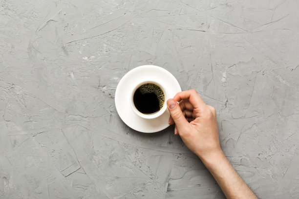 极简风格的女人手拿着一杯彩色背景的咖啡。平躺，俯视图卡布奇诺杯。空白的地方文字，复制空间。咖啡上瘾。俯视图，平铺图片下载