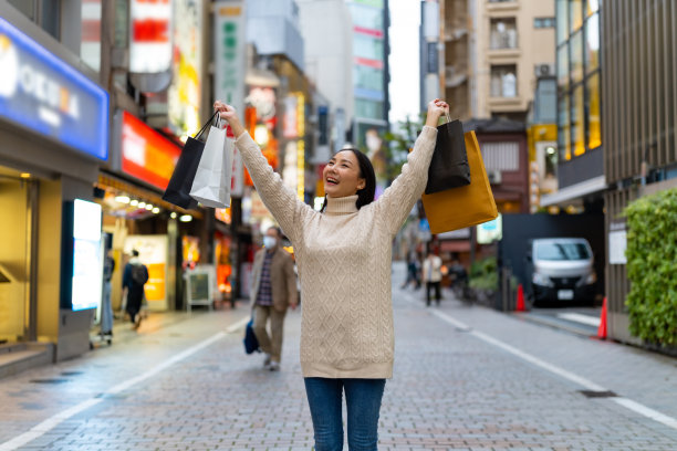 傍晚，日本东京涩谷区，一名亚洲妇女拎着购物袋走在街上。图片下载