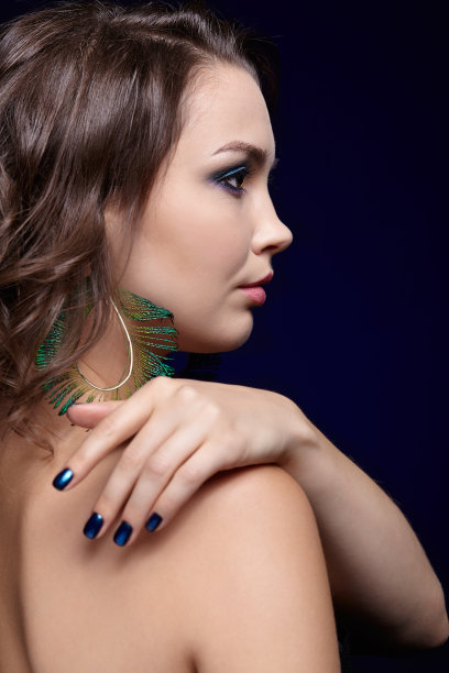 美丽的黑发女人肖像在黑色背景和孔雀羽毛耳环图片下载