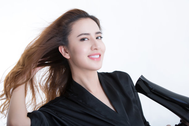 年轻美丽的中国女人用吹风机吹干头发，在白色背景- stock照片图片下载