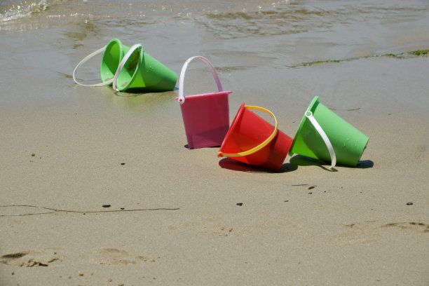 湿沙滩上的塑料沙桶图片下载