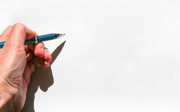 左手少年拿着一支蓝墨水笔，一张白纸——空白的表面上有纹理和手的影子图片下载