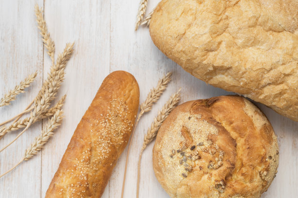 新鲜的白小麦面包，圆形经典，意大利面包，法国法棍面包，麦穗和谷物在白色木制背景俯视图。做面包，烘焙，健康食品。面包的背景。光模型图片下载