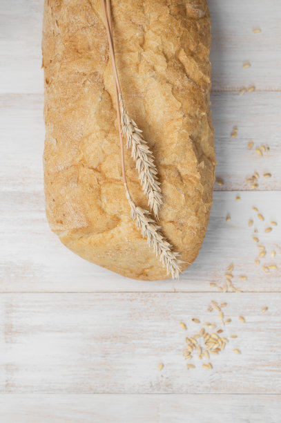 新鲜的白色经典小麦面包ciabatta，麦穗和谷物在白色木制背景上俯视图。做面包，烘焙，健康食品。面包的背景。为面包做广告的轻型模型图片下载