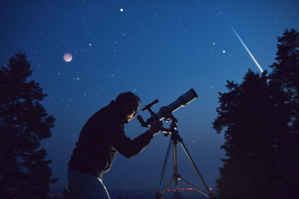 一个人的剪影，望远镜，星星，行星和夜空下的流星。图片下载