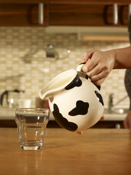 女人手倒一杯牛奶。图片下载