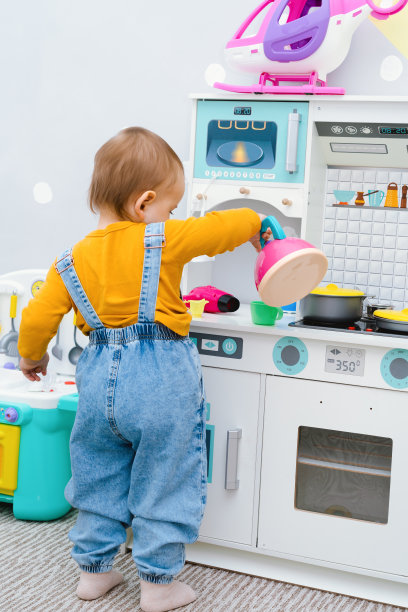 在孩子们的厨房里，一个小女孩从一个玩具茶壶里倒茶图片下载