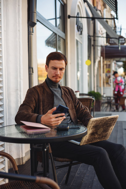 忙碌的商人用智能手机和笔记本电脑在街边咖啡馆工作图片下载