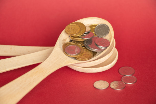 木勺和硬币在一个红色的背景特写图片下载