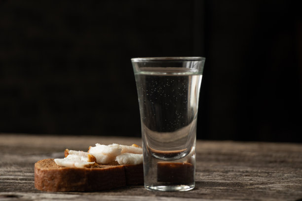 在厨房的一张木桌上，一杯伏特加和一块黑面包配上熏肉作为午餐图片下载