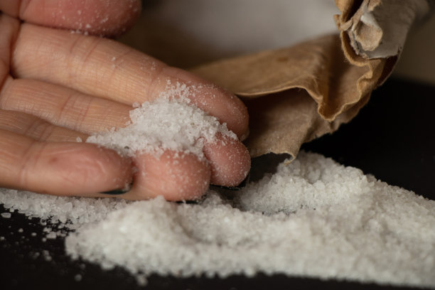 黑背景上散落的岩盐特写及女人的手图片下载