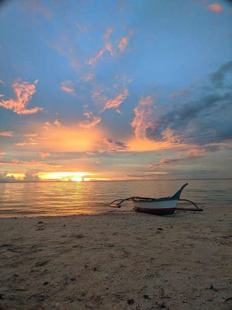 在美丽的日落期间，一艘帆船在沙滩上拍摄的垂直照片图片下载