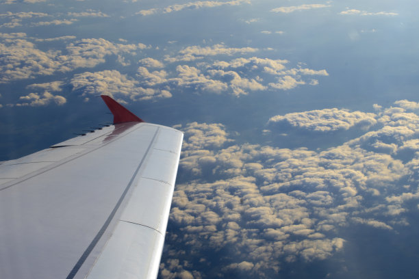 高空飞行:从机舱俯瞰。在云层上飞行的飞机的机翼。图片下载