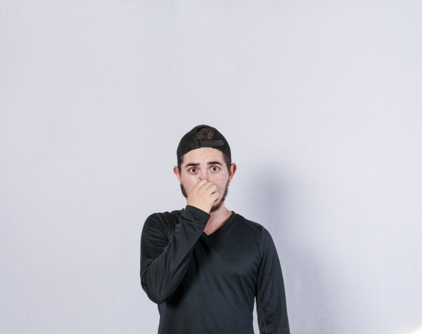 一个男人捂住他的鼻子，一个人的脸令人不快的气味，拉丁裔男子捂住他的鼻子图片下载