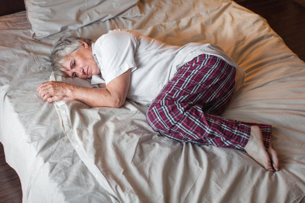 悲伤不快乐的老年妇女坐在卧室的床上图片下载