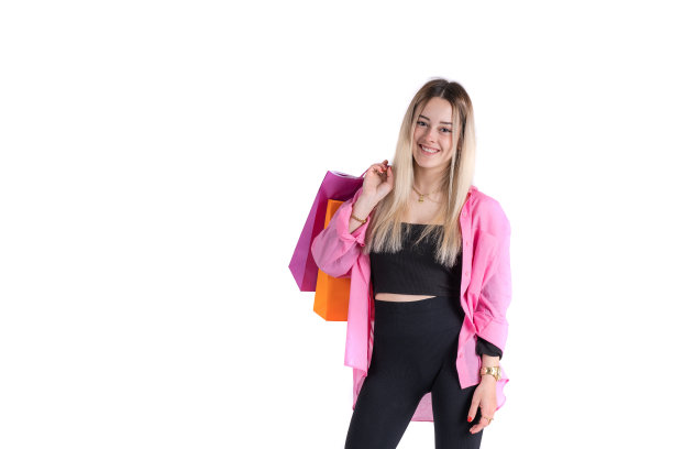 年轻女子站在那里，肩上扛着购物袋，看着镜头图片下载