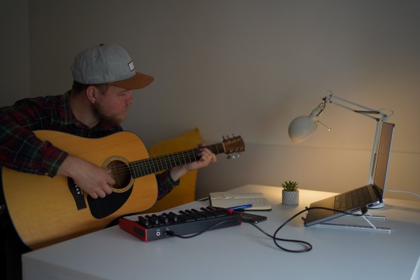 男吉他手在家里的录音棚，弹吉他的同时通过视频电话彩排，与乐队的朋友图片下载