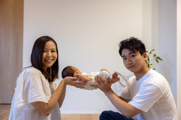 客厅里父母亲抱着刚出生的婴儿的照片图片下载