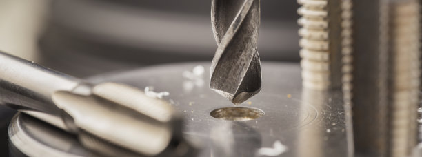 金属钻头在带刨花的工业钻床上的铝坯上打孔。金属加工行业。多刀和立铣刀。图片下载