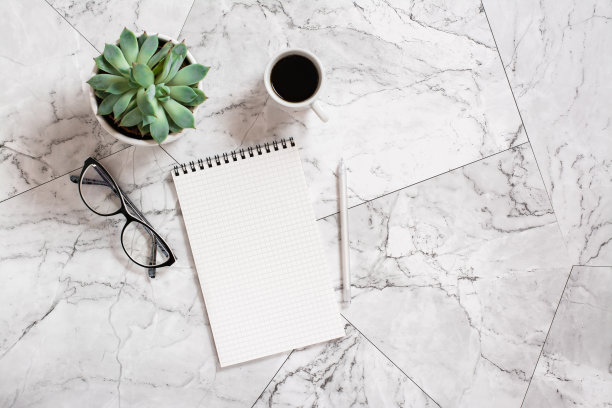 笔记本，钢笔，玻璃杯，多汁饮料和一杯黑咖啡放在大理石瓷砖上。图片下载
