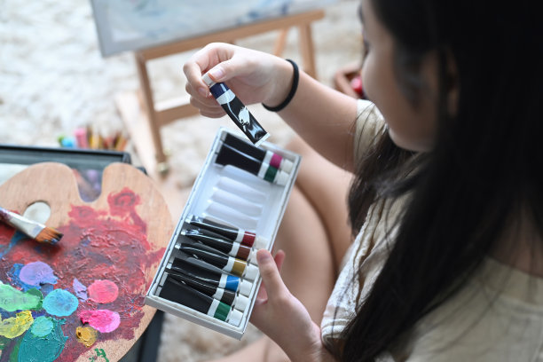 小女孩的手选择丙烯酸油漆管为她的艺术作品裁剪的镜头。图片下载