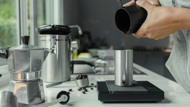 用手将煮好的咖啡粉倒入装有意式浓缩咖啡的器具工具的杯子中冲泡意大利摩卡壶，咖啡在厨房家中。准备喝图片下载