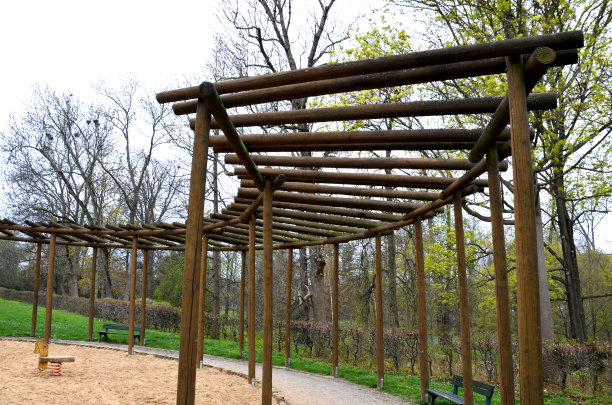 圆形的藤架，由木杆制成的棚架围绕着沙坑，为孩子们提供了玩耍的元素。周围是一条小路和草坪。妈妈们休息的长凳。日本式的中国式赌注图片下载