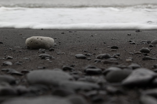 潮湿的黑色火山海岸与泡沫海浪冲浪，灰色的沙子，黑色的石头，纹理，背景。图片下载