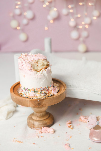 砸蛋糕的场景-白色的小床和粉红色的婴儿鞋，蛋糕的残留物凌乱的背景。图片下载