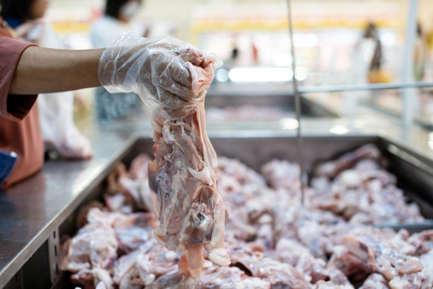 戴着塑料手套的女性在超市挑选鸡肉图片下载