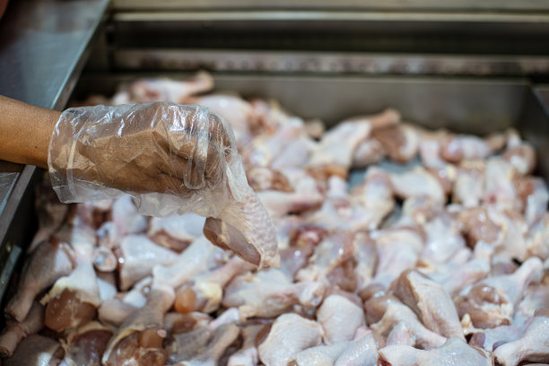戴着塑料手套的女性在超市挑选鸡肉图片下载