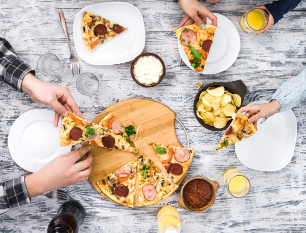 人们吃披萨配薯条和酱汁图片下载