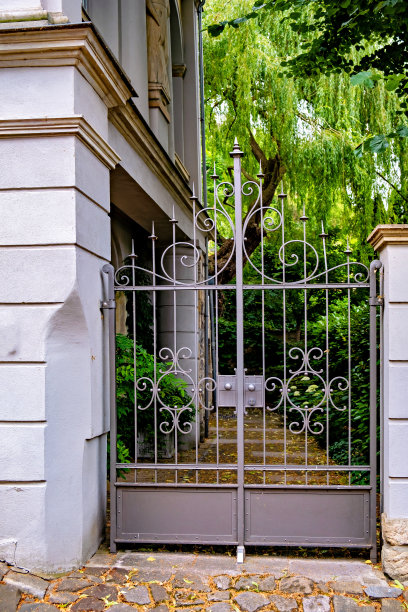 封闭的金属门通往德国的房子，有一条砖砌的人行道通向它图片下载