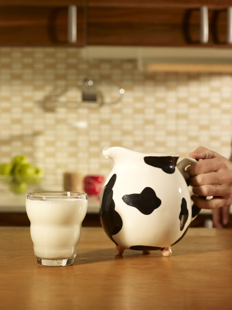 女人手倒一杯牛奶。图片下载