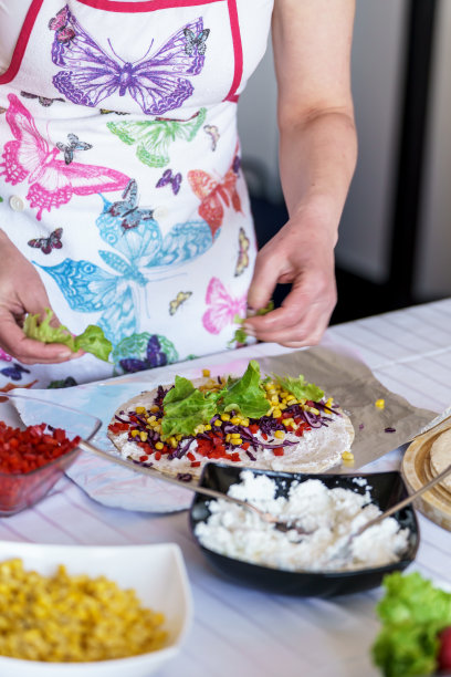 一个女人用肉和蔬菜做玉米饼的照片。图片下载