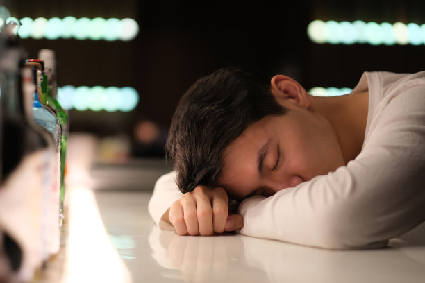 英俊的亚洲年轻人在吧台上喝醉了图片下载