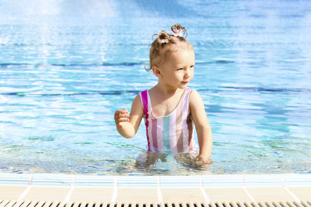 一个欧洲人模样的有趣小女孩在一个炎热的阳光灿烂的日子里在游泳池里。幸福童年的概念。旅游和娱乐的概念。旅馆或度假旅游的广告图片下载