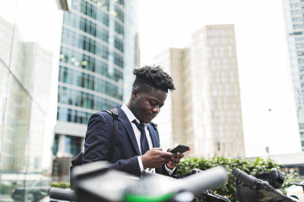 年轻的黑人商人使用手机应用租用电动滑板车图片下载