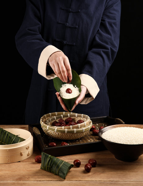 厨师正在包粽子，场景在厨房，暗背景图片下载