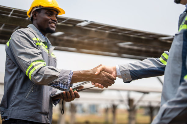 专业工程师下班后在现代太阳能农场握手。技术人员在太阳能电池工厂检查太阳能电池板设备。生态与替代能源概念。图片下载