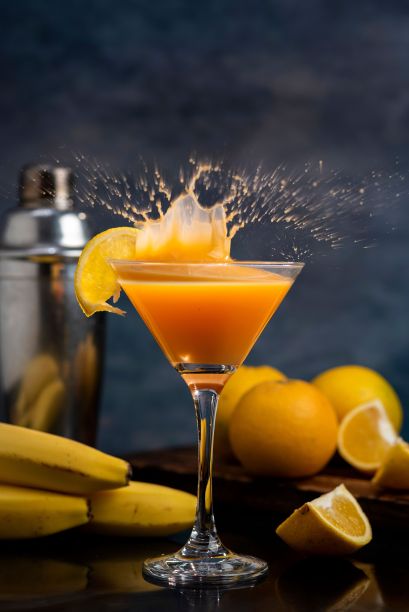 一个充满活力的鸡尾酒杯的特写，里面装满了橙汁摇瓶、成熟的橙子和香蕉图片下载