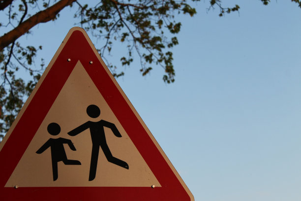 路牌上的插图是一个男人牵着一个孩子的手，背景是蓝天和一棵树图片下载
