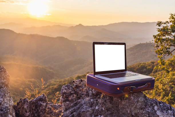 笔记本电脑在岩石山日落背景。图片下载